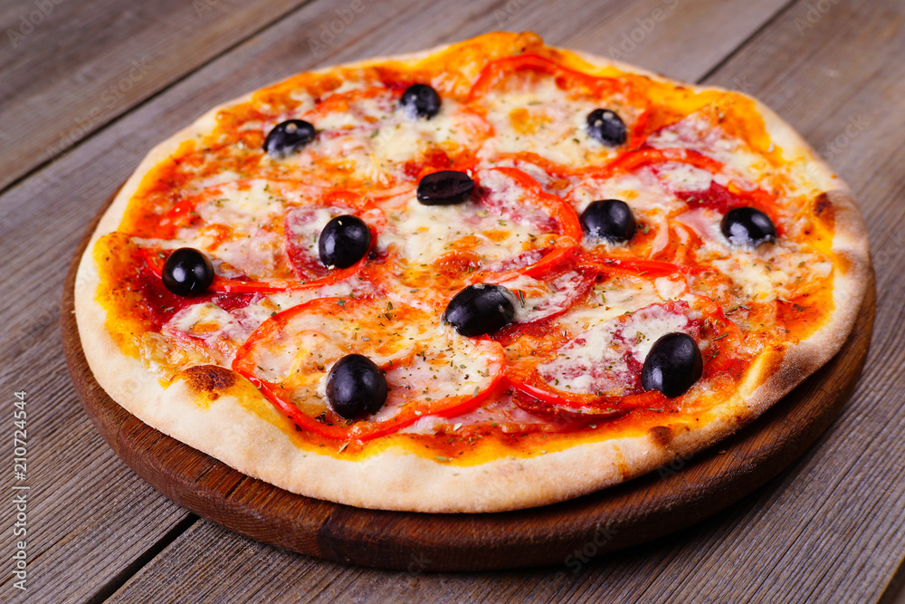 Delicious sliced pizza with salami and black olives on wood, close up. Italian food, restaurant menu photo