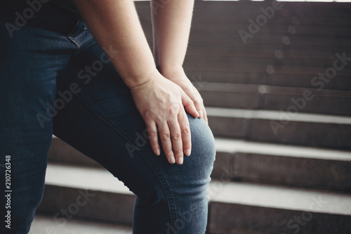 Overweight woman suffering from knee pain stepping on stairs. Excess weight, joint overload, health care and medical concept
