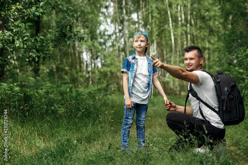 A man with a backpack, a father and his son on a hike, walking during walks in the woods. Family life, pastime with the family, the upbringing of children.