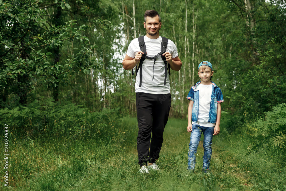 A man with a backpack, a father and his son on a hike, walking during walks in the woods. Family life, pastime with the family, the upbringing of children.