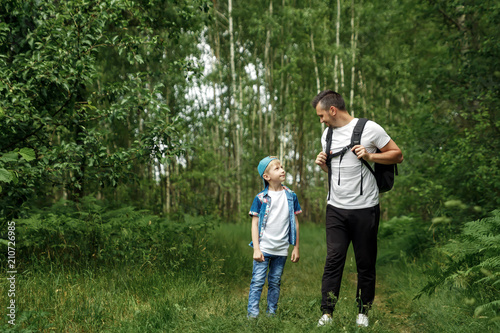 A man with a backpack, a father and his son on a hike, walking during walks in the woods. Family life, pastime with the family, the upbringing of children.