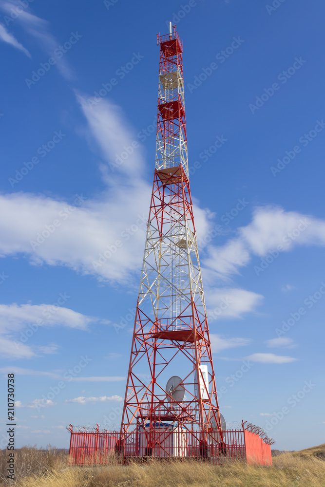 A red white telecommunications tower with a blue sky and white clouds. A red white telecommunications tower with a blue sky and white clouds.