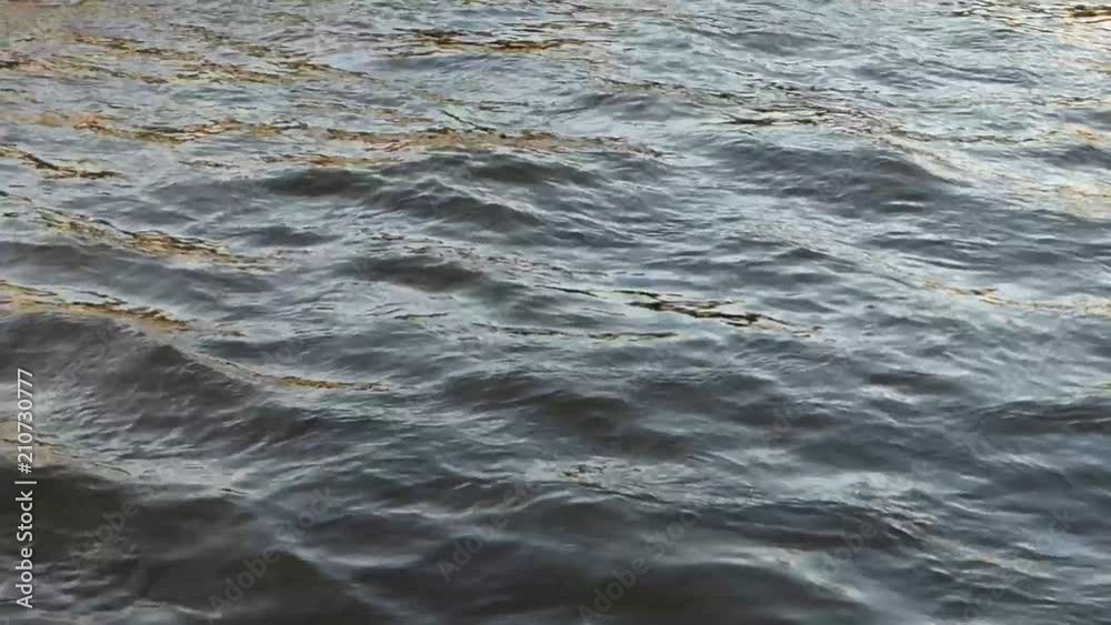 Cold water of wide northern river. Dark surface with small waves and some sun flares. Natural background. Somewhere in Russia. Cold water of wide northern river. Dark surface with small waves and some sun flares. Natural background. Somewhere in Russia.