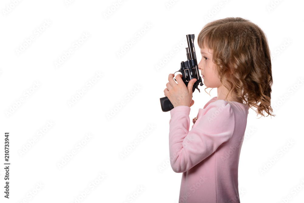 Little girl in pink dress holds in hands a black revolver on a white background. Isolated Little girl in pink dress holds in hands a black revolver on a white background. Isolated