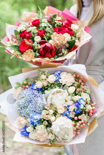 Fototapeta Naklejka Na Ścianę i Meble -  Young girl holding two a beautiful spring bouquets. flower arrangement with hydrangea and peonies. Color light blue and red. The concept of a flower shop, a small family business