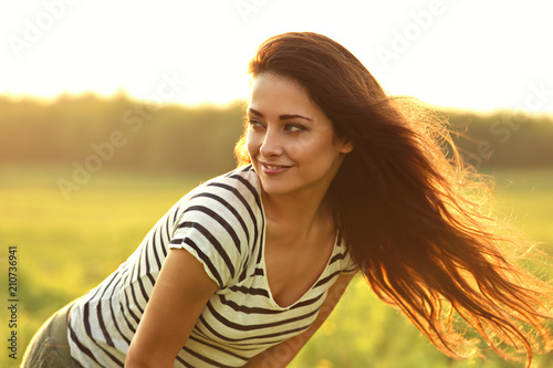 Beautiful smiling young woman looking happy with long amazing bright hair on nature bright sunset summer background. Closeup portrait © nastia1983
