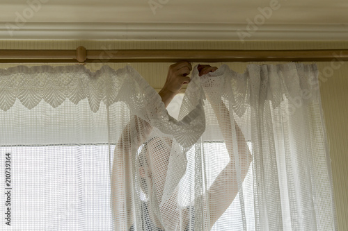 Woman hanging curtains on windows