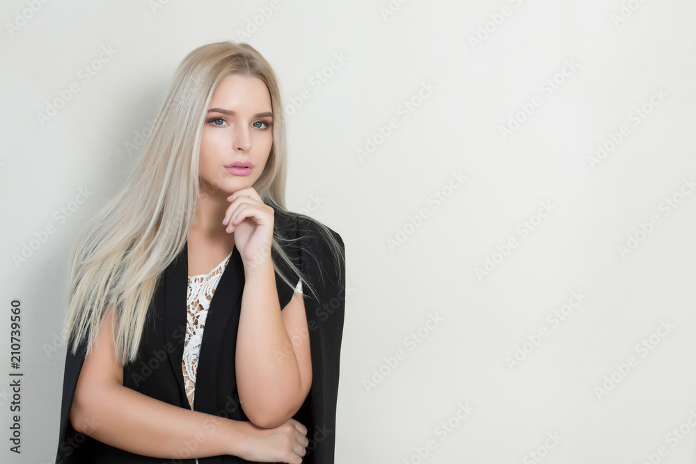 Amazing blonde model in black costume and lace blouse posing against grey wall. Empty space Amazing blonde model in black costume and lace blouse posing against grey wall. Empty space