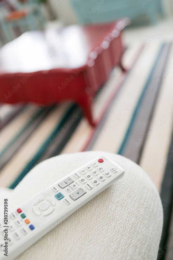 remote control. Program switching or button pressing on TV keypad. Bright living room. Morning european home. remote control. Program switching or button pressing on TV keypad. Bright living room. Morning european home.