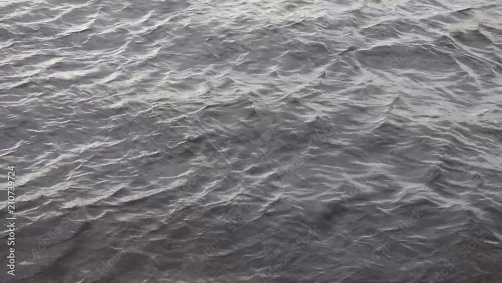 Cold water of wide northern river. Dark surface with small waves. Natural background. Cloudy day. Cold water of wide northern river. Dark surface with small waves. Natural background. Cloudy day.