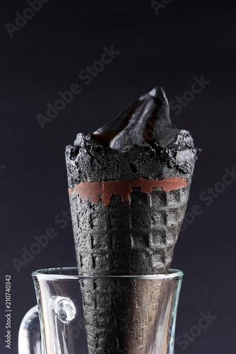 Black ice on a black background, ice cream with chocolate in waffle cone, stylish summer dessert, cold milk product for the designer, creative, copy space photo