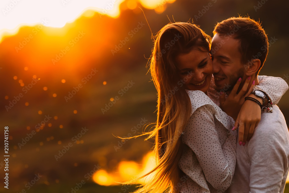 passionate hug of a couple in love on the shore of an evening la - obrazy, fototapety, plakaty 