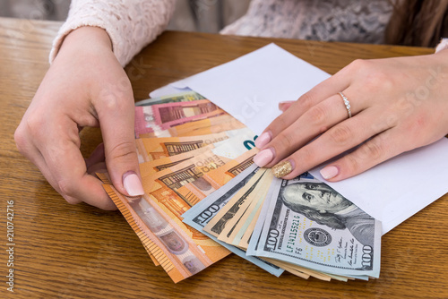 Envelope full of euro and dollar with female hands