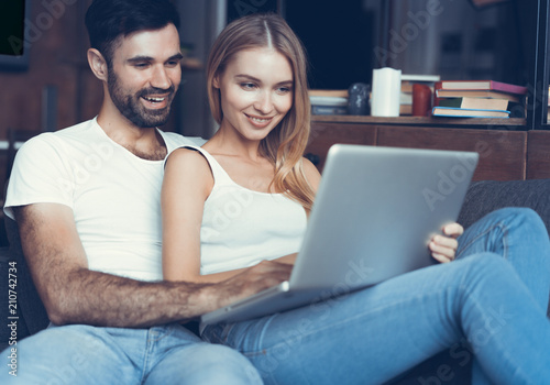 Happy couple using a laptop on the sofa.