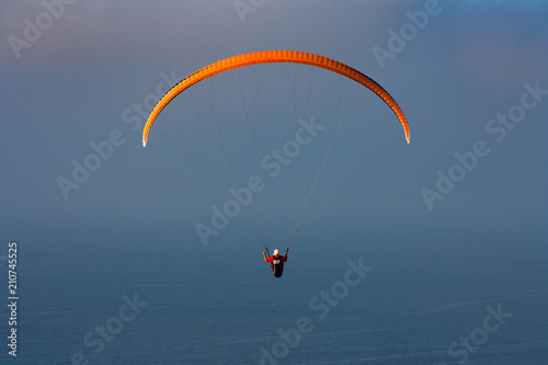 Orange Para-glider over the ocean