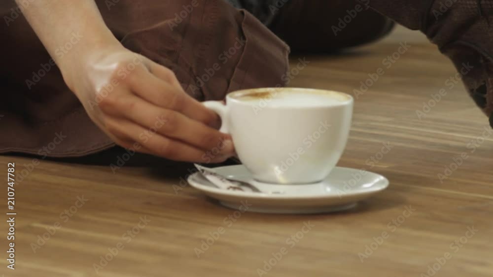 Close up, woman places coffee cup on table Close up, woman places coffee cup on table