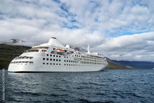 Ocean liner in sea on mountain landscape in Sejdisfjordur, Iceland. Cruise ship in sea with mountains on cloudy sky. Cruising for pleasure. Summer vacation and trip. Adventure and discovery © be free