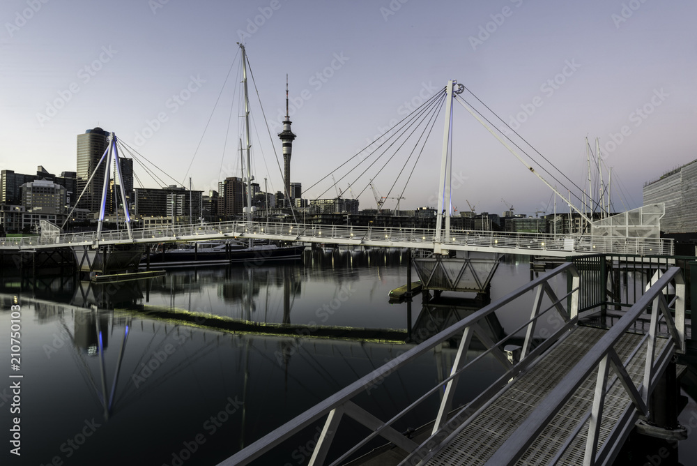 Auckland skyline seen from Viaduct Harbour over the pedestrian bridge, at dawn. Auckland, New Zealand.