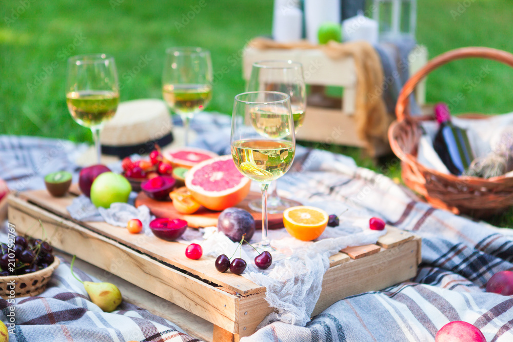 Picnic background with white wine and summer fruits on green grass, summertime party Picnic background with white wine and summer fruits on green grass, summertime party