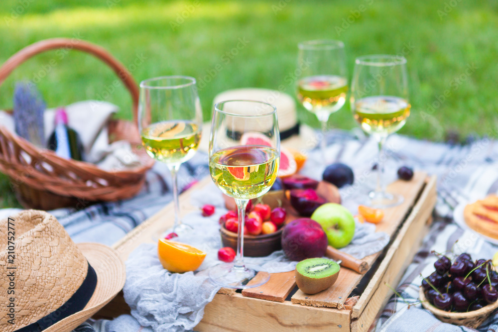 Picnic background with white wine and summer fruits on green grass, summertime party Picnic background with white wine and summer fruits on green grass, summertime party
