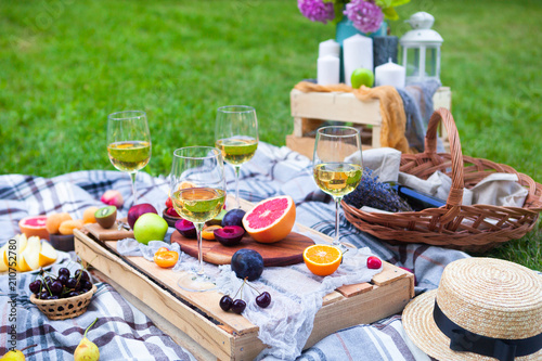Picnic background with white wine and summer fruits on green grass  summertime party