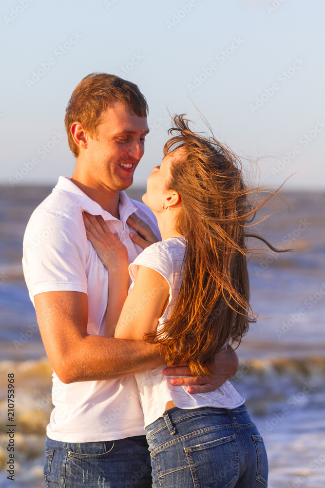 Portrait happy young couple relaxing on beach at sunset. Family traveling romantic concept Portrait happy young couple relaxing on beach at sunset. Family traveling romantic concept