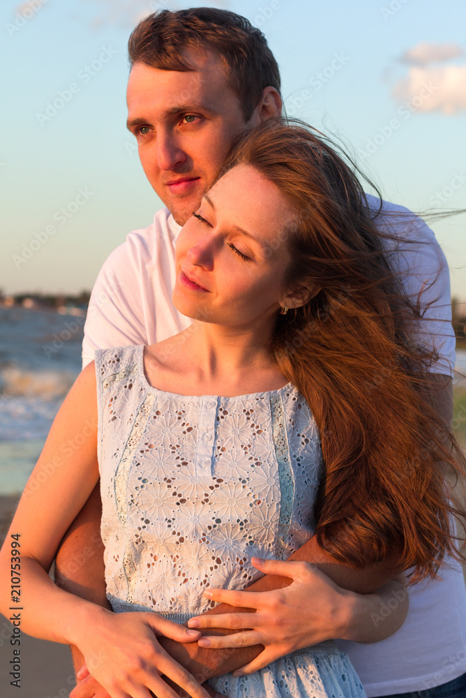Portrait happy young couple relaxing on beach at sunset. Family traveling romantic concept