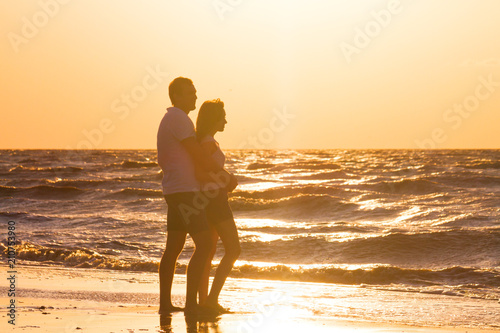 Happy young couple relaxing on beach at sunset. Family traveling romantic concept