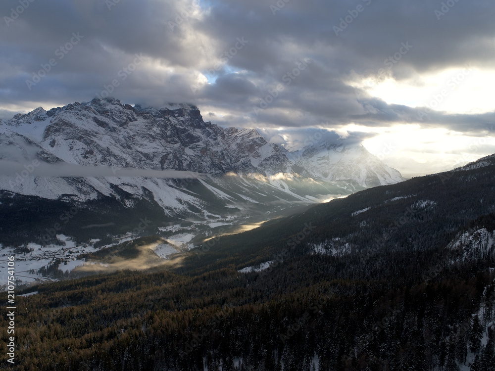 drone flying above pine tree forest on cold winter morning with sunset and alps mountain range in background drone flying above pine tree forest on cold winter morning with sunset and alps mountain range in background
