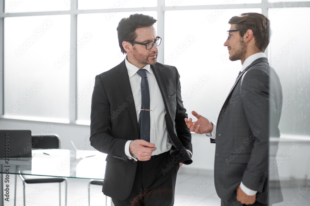 two businessmen discussing business issues standing in the office. two businessmen discussing business issues standing in the office.
