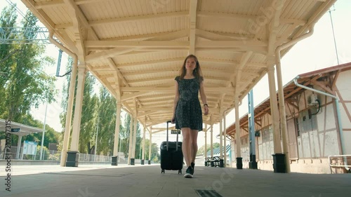 Young Slender Woman is Traveling and Walking on Vintage Train Station with Suitcase