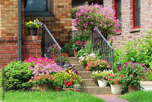 Beautiful seasonal house outdoor decoration. Scenic view with way to the main entrance  and staircase of the old style house decorated by colorful potted flowers for spring and summer season. photo