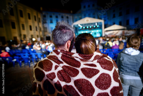 The couple shares one plaid for two on a cold night. Love heats. Evening party in the open air