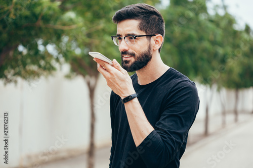 Obraz na plátne Leisure, technology, communication and people concept - young man using voice co