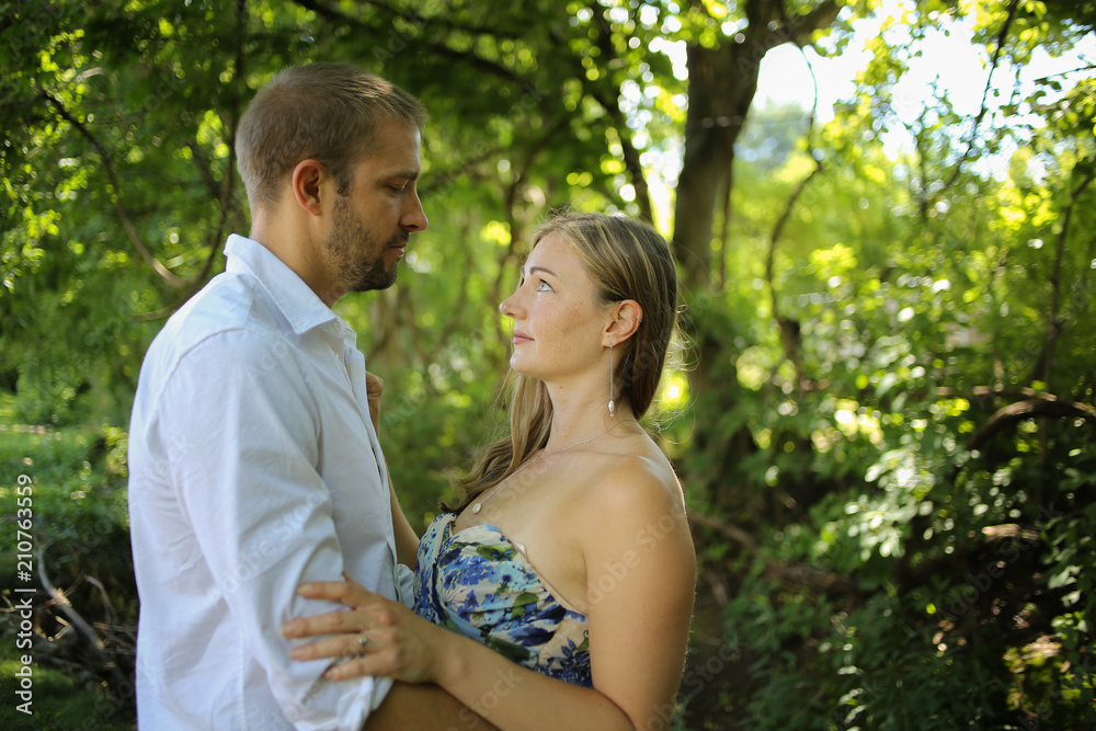 Fototapeta premium Romantic Couple Side view portrait of a Young Caucasian Couple in an Embrace with Natural Lighting Outside on a Spring or Summer Day