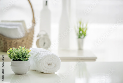 Tableau sur toile Roll up of white towels on white table with copy space on blurred living room ba