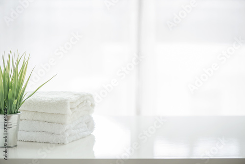 Towels and houseplant on white table with copy space