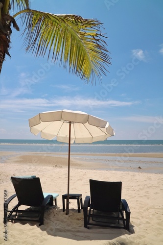 Bed beach and white umbrella on tropical beach with coconut tree in the summer morning. Nature and travel concept.
