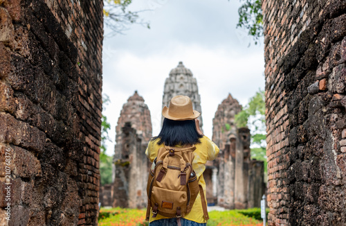 Asian tourist woman take a photo of ancient of pagoda temple thai architecture at Sukhothai,Thailand. Female traveler in casual thai cloths style visiting city concept.