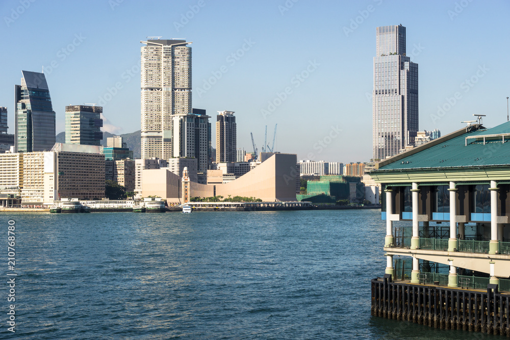 Central Star Ferry pier with the Kowloon skyline at Tsim Sha Tsui view from across the Victoria harbour in Hong Kong on a sunny day in China SAR.