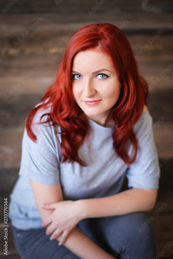 Young woman with red long hair indoor portrait on wooden background Young woman with red long hair indoor portrait on wooden background