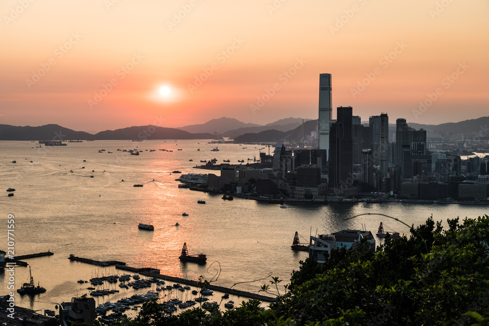 Fototapeta premium Stunning view of the sunset above the Victoria harbor in Hong Kong with the skyscraper of Kowloon Tsim Sha Tuis waterfront in the left in China