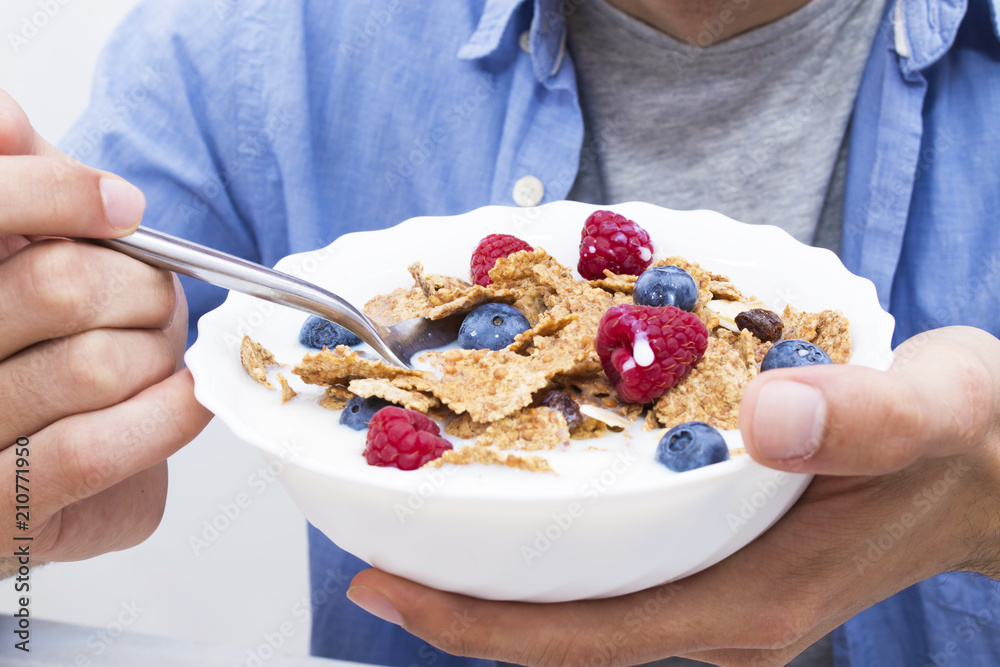 young man eating cereal with fruit young man eating cereal with fruit