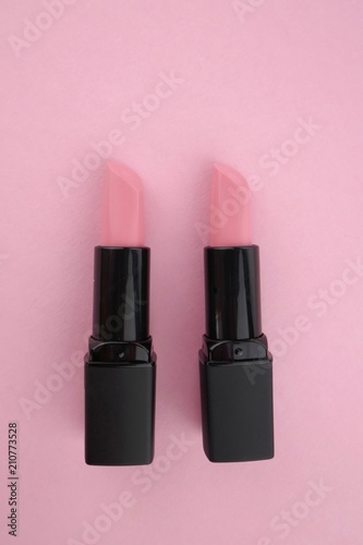 Nude lipstick.  pink lipstick in a black bottle on a pink background. Makeup and cosmetics