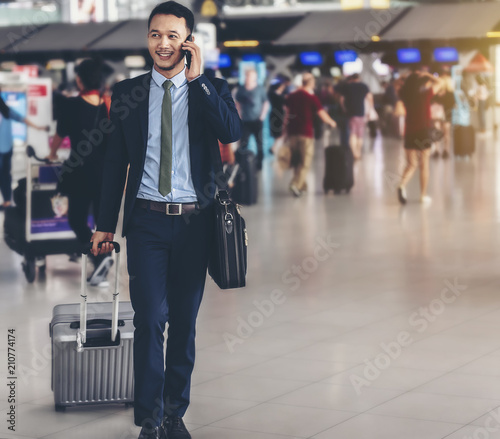 An Asian businessman is using a smartphone to get in business while waiting for a trip in the airport.