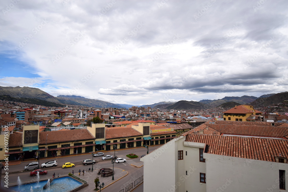 a scenic aerial shot of houses and shops with their distinctively European orange roofs in Cuzco, Peru, from the top floor of a building on a cloudy and sunny day 