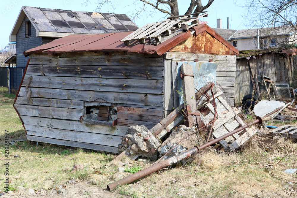 The ruined wooden shed is located on the country backyard