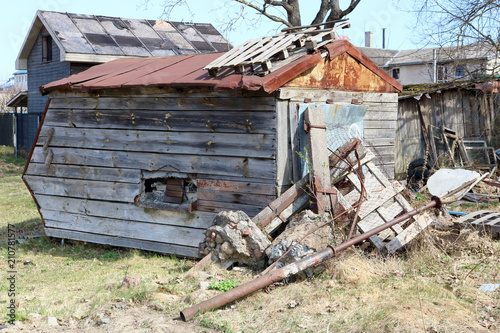The ruined wooden shed is located on the country backyard