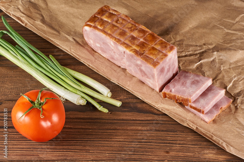 ham on kraft paper with green onion and tomat on a wooden background photo