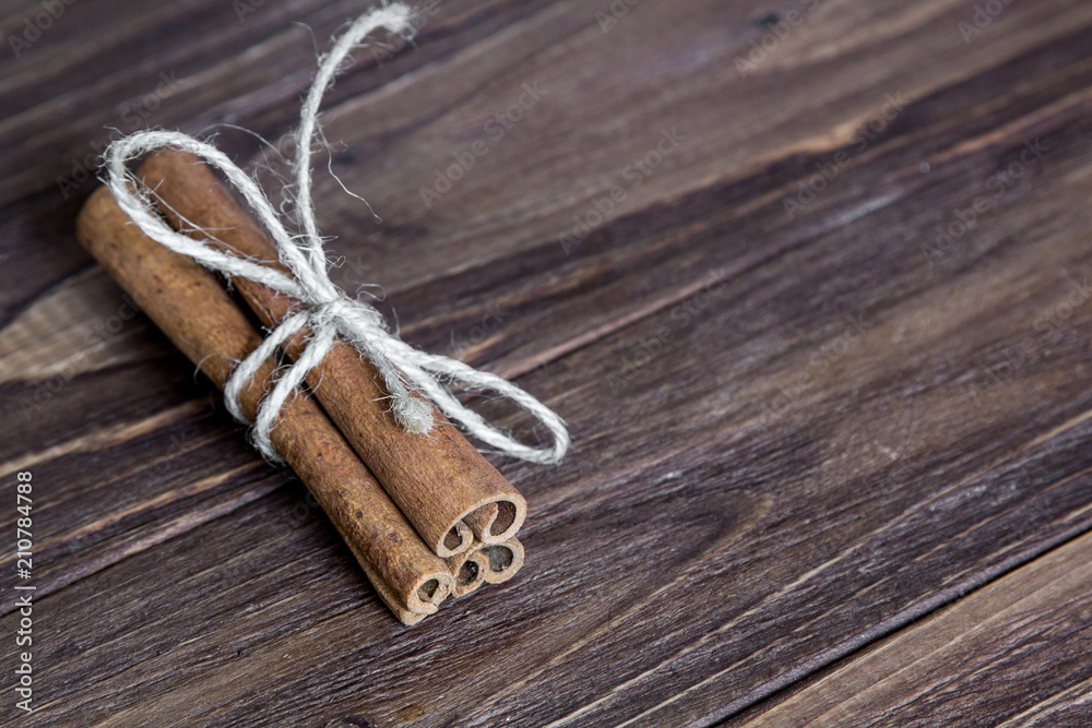 three cinnamon stick tied with rope, at the brown wooden table three cinnamon stick tied with rope, at the brown wooden table
